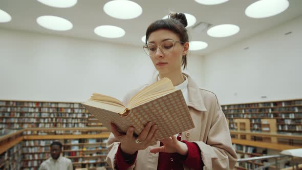 Young Woman Reading Book in Library