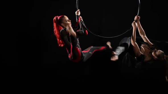 Two Slim Woman in Shiny Costumes Spinning Air Hoop Doing Arabesque Trick Simultaneously