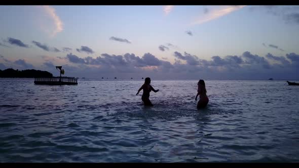 Women best friends on luxury resort beach holiday by blue green lagoon with white sandy background o