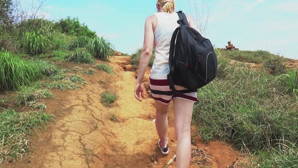 traveler girl walking along a trail on a tropical island with palm trees and sea