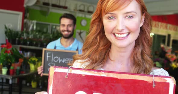 Florists holding signboards in flower shop