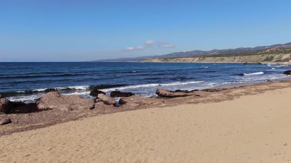 Sandy Beach of Mediterranean Sea with Dark Blue Waves Splashing in Sunrays