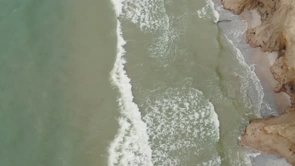 Aerial View of Ocean Waves Crashing Against the Steep Coastline on a Wooded Coast