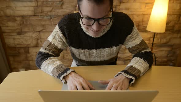 Happy Young Man with Eyeglasses Using Laptop at Home