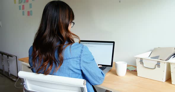 Female executive using laptop white having coffee