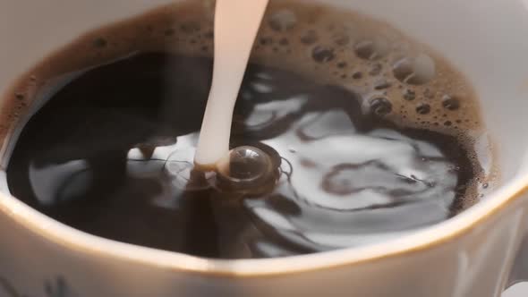 Hot Coffee in Cup with Milk Being Poured in