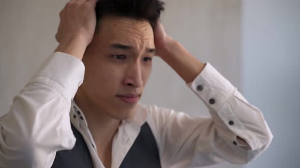 Asian Man Grabs Head with Hands Showing Emotion of Regret