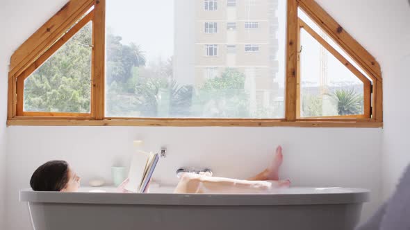 Woman reading a book while relaxing in a bathtub