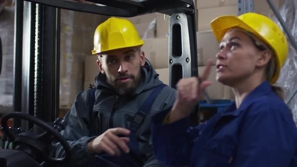 Forklift Operator Discussing Work with Female Colleague