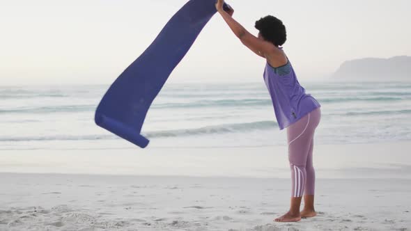 African american woman with yoga mat on sunny beach