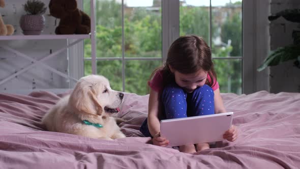 Girl Watching Funny Cartoon with Pet Dog Indoors