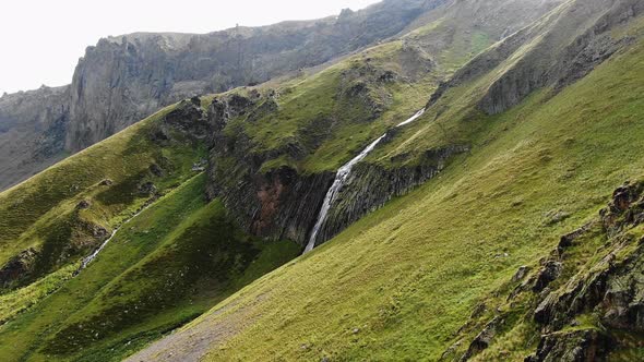 Large Hillside with Rocks Thick Grass on Top and Waterfall