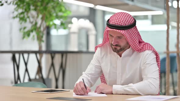 Focused Arab Businessman Writing on Paper Paperwork