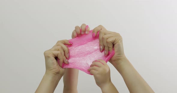 Woman and Child Hands Playing Oddly Pink Slime on White Background