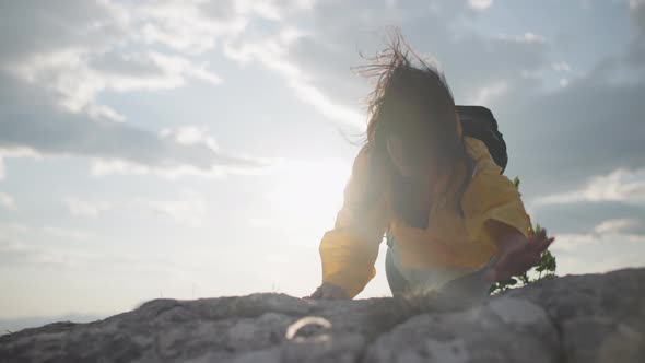 The Girl Clings to the Stones with Her Hands While Climbing Up the Mountain