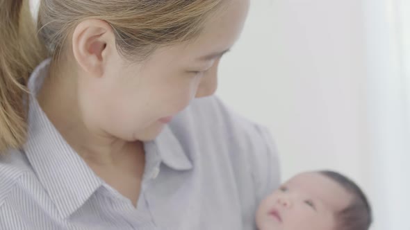 Happy Asian mother hugging her newborn baby daughter at home, Happiness moment of Asian family.