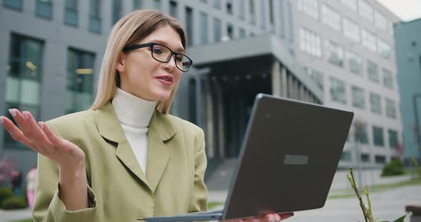 Woman in Glasses Standing by Modern Building Offices During Using a laptop.