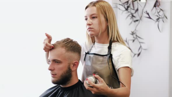 Stylist Doing Hair Styling with Spray in Beauty Salon