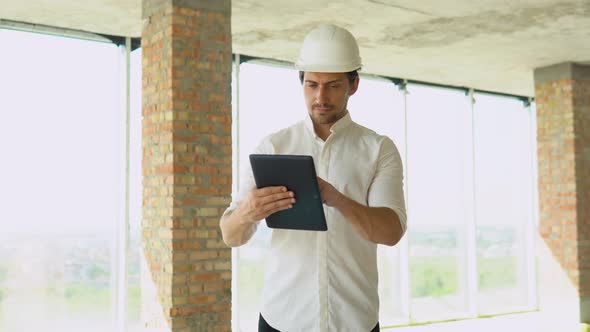 Engineer Developer in Helmet with Tablet Inspecting Building alt