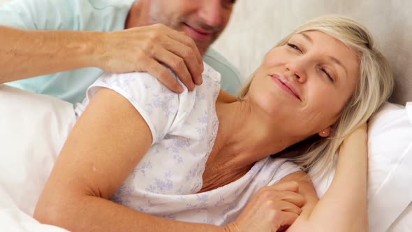 Couple Relaxing in Bed and Smiling at Camera
