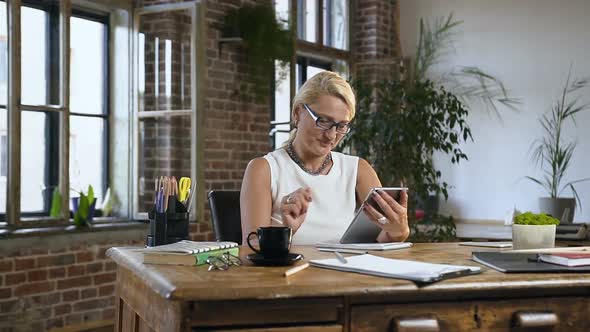 Middle-aged Blonde Sitting at a Wooden Table in Classical Style Office