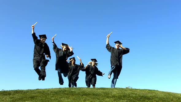 Graduates running over hill, slow motion