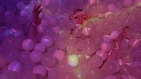 Young Woman Playing with Balls in a Dry Pool Spotlight with Abstract Video Art
