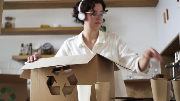 Young Active Woman Dances In White Headphones Listens To Music Stacking Sorted Garbage From