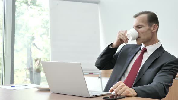 Businessman Drinking Coffee at Work