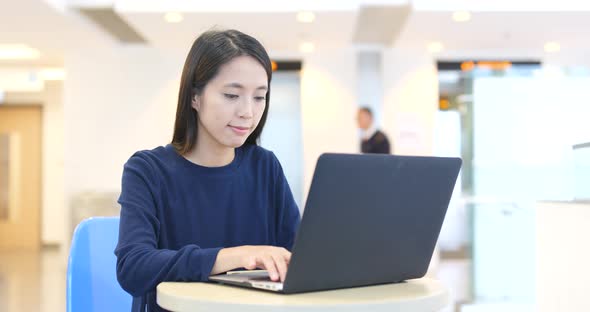 Woman working on notebook computer inside building