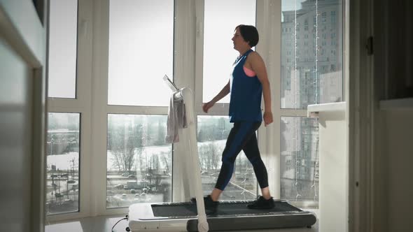 Woman is finishing to run on treadmill, pressing stop button