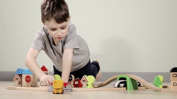 Cute boy plays with a wooden train, takes him across the bridge on flights. Wooden educational toys.