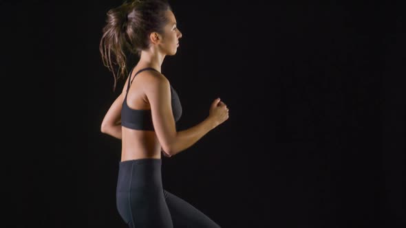 Athletic woman working out in front of a black background