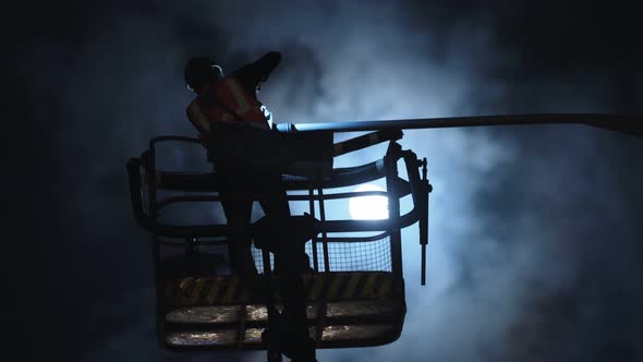 silhouette of a electric engineer working on a street lamp with the moon in the background