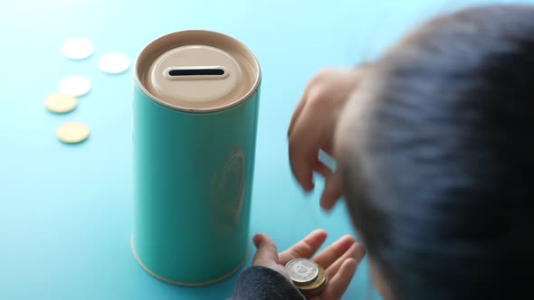 Rear View of Child Girl Saving Coins in Jar