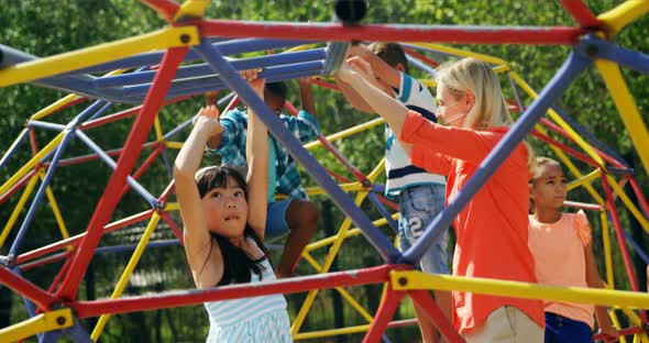 Trainer assisting schoolkids while playing in playground