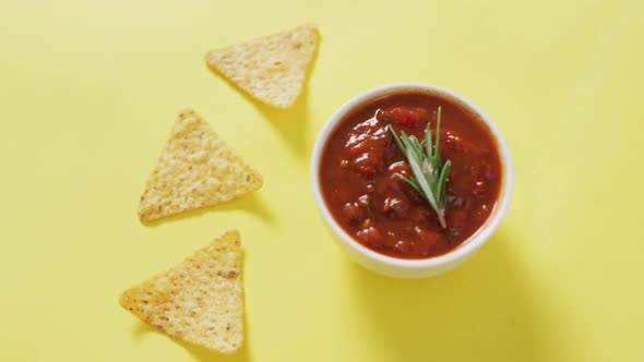 Video of tortilla chips and salsa dip on a yelllow surface