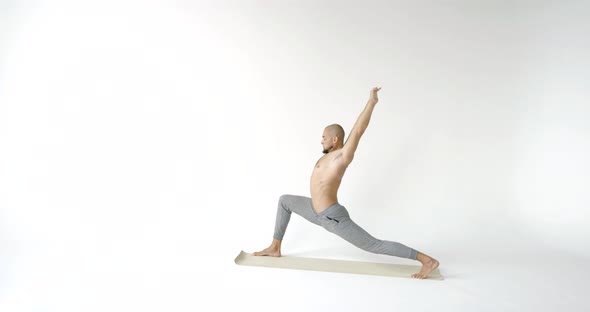 Muscular Male Yogi Doing the Pose of a Warrior and Goes Into a Pose the Downward Facing Dog. White