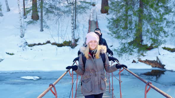 A Woman and a Man Walking on a Suspension Bridge in a Snowy Nature Park