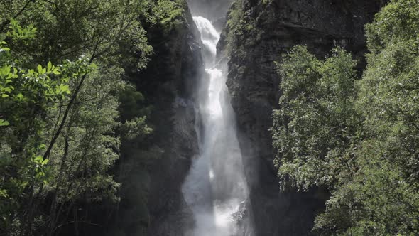 Static shot in slowmotion of the La Pisse waterfall. The sunlight creates beautiful shadows with the