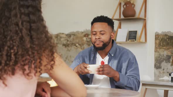 Happy diverse couple spending time together at cafe, drinking coffee and talking