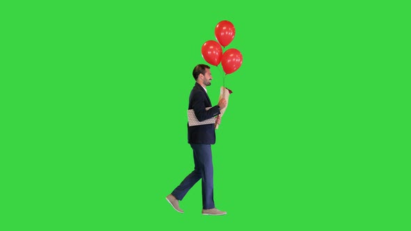 Elegant Man in a Suit with a Bouquet of Flowers a Gift and Balloons Walking on a Green Screen Chroma
