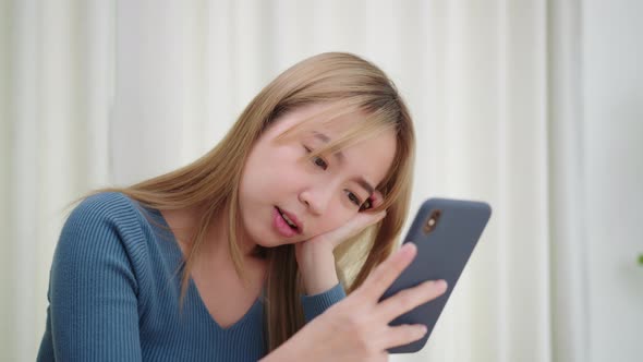 Upset Asian woman looking at smartphone screen feels sad and disappointed with bad news
