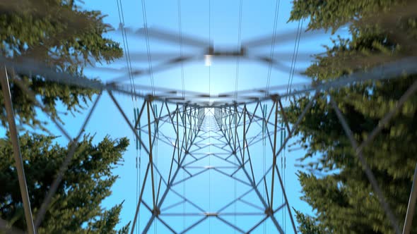 High voltage electricity pylons in a mountain forest. Blue sky in background. 4k