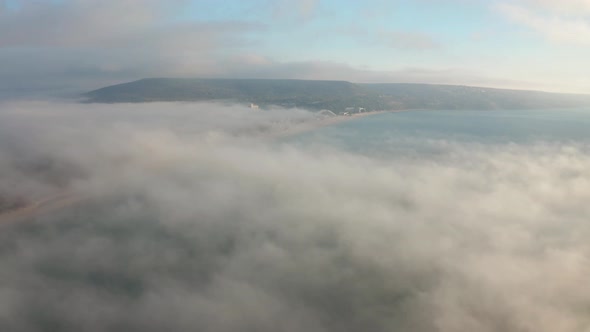 Low clouds over a sea coastline at sunrise alt