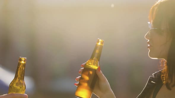 Attractive Woman Drinking Beer With Friend At Party Outdoors