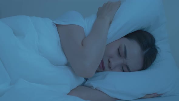 Asian beautiful frustrated girl in pajamas lying down on bed in dark night sleep in bedroom in house