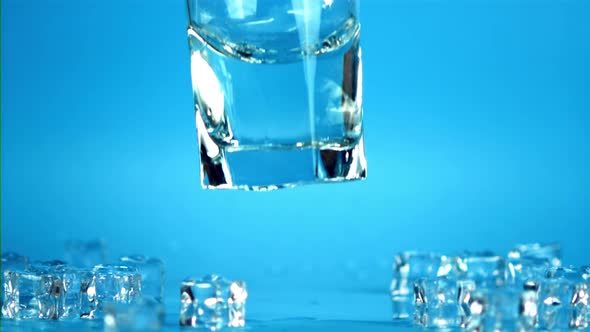 Super Slow Motion Glass with Water Falls on the Table with Splashes