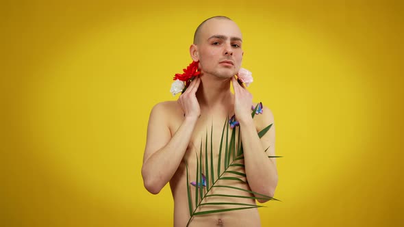 Expressive Male Queer Covered with Flowers and Butterflies Posing at Yellow Background