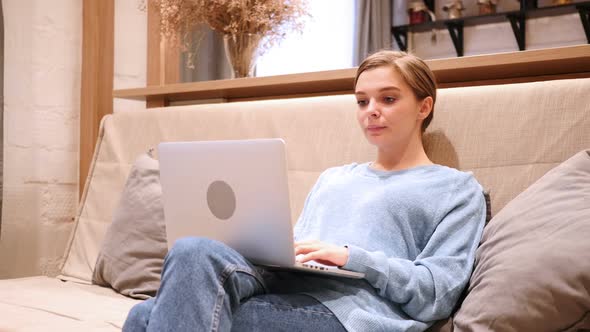 Excited Woman Celebrating Success While Working on Laptop Sitting on Couch